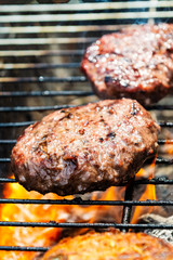 Burgers are cooking on grill with open flames