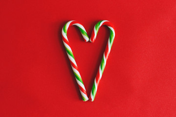 Christmas candy canes on red background. Heart.