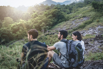 Fototapeta premium Young tourists spend their holidays in the nature and forest tourism and looking at something exciting, and the beauty of refreshing from nature while sitting resting on the rocks.