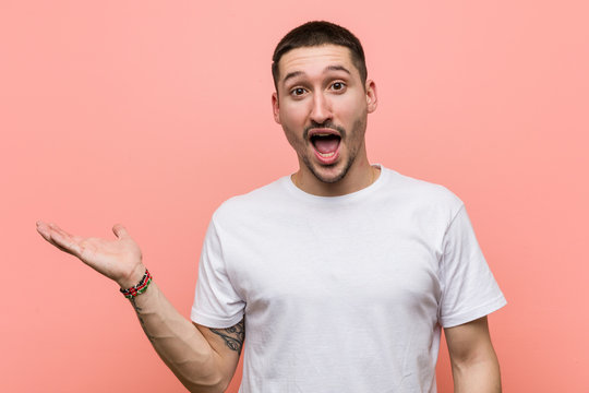 Young casual man impressed holding copy space on palm.