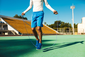 Close up African American sportsman jumping on skipping rope during workout at stadium