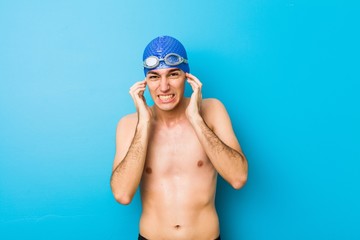 Young swimmer man covering ears with hands.