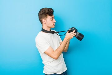 Teenager caucasian man taking photos with a reflex camera