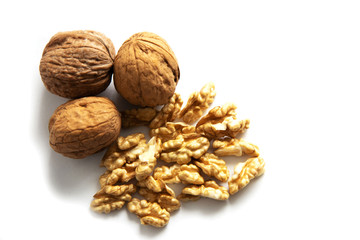 a handful of peeled walnuts and three whole walnuts lie nearby on a white background. Place for text