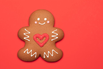 Christmas Gingerbread man biscuit with red heart icing on red background