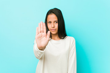 Young pretty hispanic woman standing with outstretched hand showing stop sign, preventing you.