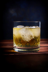 WHISKEY GLASS WITH ICE AND ON DARK BLUE BACKGROUND WITH TEXTURE