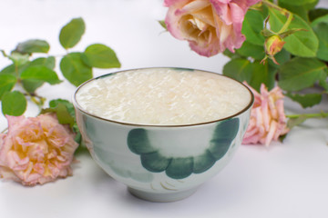 Brazilian dessert made of tapioca pearls called sagu in cream flavor in a bowl with roses in the background