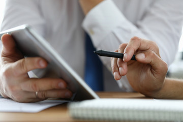 Focus on male hand holding stylos. Colleague with modern tablet explaining conditions of contract. Businessmen discussing new start-up. Business meeting concept. Blurred background