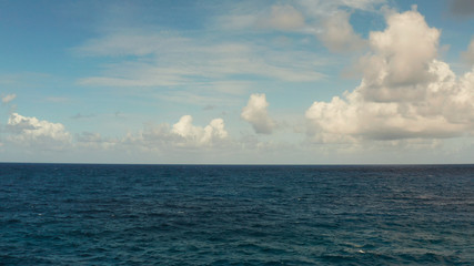 Blue ocean with waves and blue skies with clouds. Blue water and sky landscape, top view. Water cloud horizon background.
