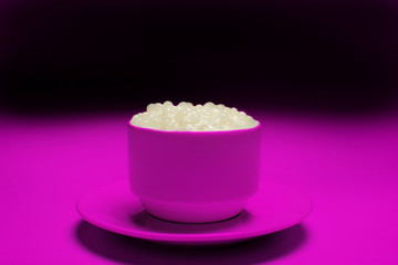 Brazilian dessert made of tapioca pearls called sagu in cream flavor in a magenta cup and background