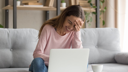 Cheerful girl laughing watching funny online video on laptop