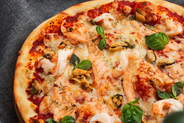 Seafood Italian pizza with shrimp,squid, mussels, fresh herbs and mozzarella on a crusty base viewed from above on Gray background. Horizontal photo.