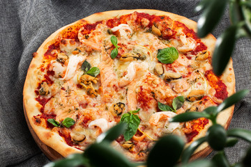Seafood Italian pizza with shrimp,squid, mussels, fresh herbs and mozzarella on a crusty base viewed from above on Gray background. Horizontal photo.