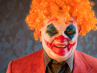 Portrait of male clown in pink dressed for Halloween. actor made makeup of crazy, evil clown faced...