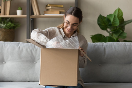 Smiling young woman customer unpack box open parcel at home