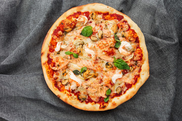 Seafood Italian pizza with shrimp,squid, mussels, fresh herbs and mozzarella on a crusty base viewed from above on Gray background. Horizontal photo.