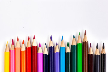 Set of colored pencils at the bottom of the frame in a row on a white background. Flat lay style.