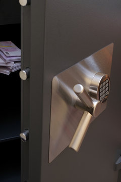 The open door of the safe with a digital code lock in which the euro banknotes lie.