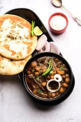 Pindi Chole Kulche or roadside choley Kulcha popular in India and pakistan is a popular streetfood. It's a spicy Chickpea or chana curry served with Indian Flat Bread. selective focus