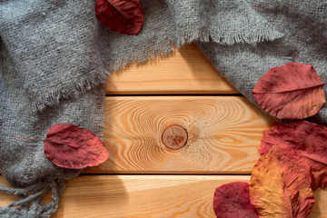 Flat lay view of grey scarf and autumn leaves   on wooden background