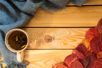 cup of tea, grey scarf on a wooden background. autumn mood.flat lay
