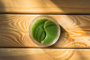 Green eye patches on wooden background. Eyelid skin care concept