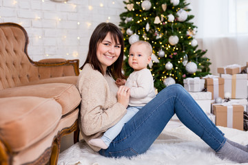 christmas, happiness and family concept - portrait of happy mother and little daughter near decorated christmas tree
