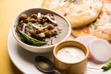 Pindi Chole Kulche or roadside choley Kulcha popular in India and pakistan is a popular streetfood. It's a spicy Chickpea or chana curry served with Indian Flat Bread. selective focus