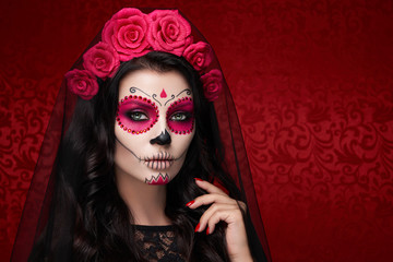 Portrait of a woman with sugar skull makeup over red background. Halloween costume and make-up....