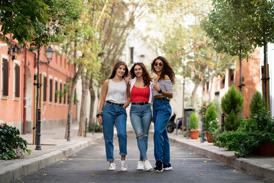 Three female friends laughing in the street