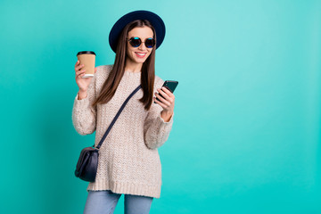 Portrait of stylish trendy positive girl use her cell phone read blogs wear white jumper knitted...