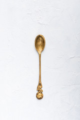 Vintage small brass spoon on white table background top view flat lay.