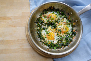 pan with spinach and fried eggs, spices and herb garnish, protein-rich dish for low carb diet on a...