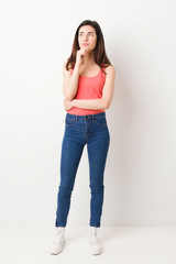 Fototapeta premium Full body young woman on white background looking sideways with doubtful and skeptical expression.