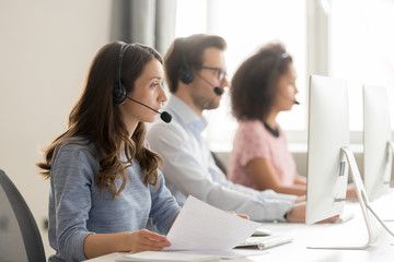 Call center worker holding paper talking with client use headset