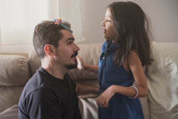 Father playing with daughter with diadem at home