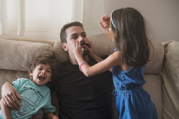 Father and daughter at home playing in sofa
