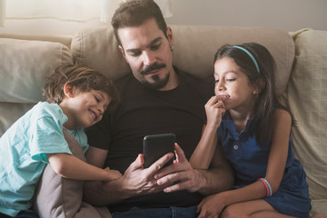 Father son and daughter at home looking phone