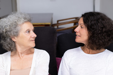 Senior mother and adult daughter discussing family issues. Middle aged woman and elderly lady sitting in living room and talking. Family discussion concept