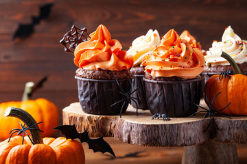 Halloween cupcakes and pumpkins on dark background. Sweets for holiday party.