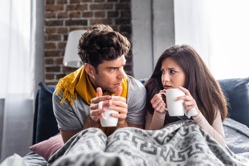 Sick girlfriend and boyfriend holding cups with tea