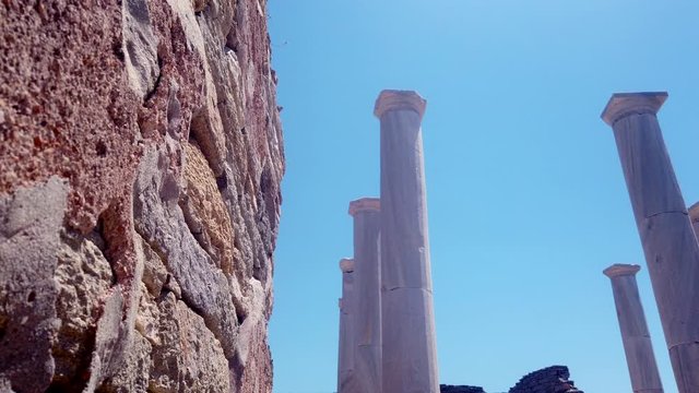Revealing slide shot of Delos Archaeological Site pillars, Greece