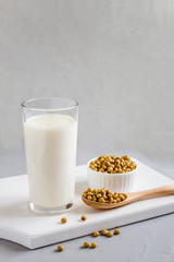 Glass with soy milk and soybeans in a plate on the table. Vegetable drink. Vegetarian food. The concept of healthy eating. Space for text.