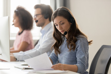 Customer support phone operator sitting at workplace holds read document - obrazy, fototapety, plakaty