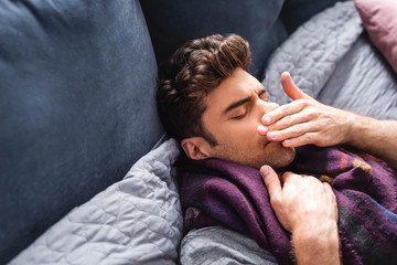 sick and handsome man in scarf with closed eyes lying in bed