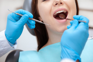 Cropped close up of a female patient with healthy teeth having dental examination by professional dentist