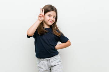 Fototapeta premium Cute little caucasian girl showing victory sign and smiling broadly.