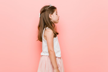 Little girl wearing a princess look gazing left, sideways pose.