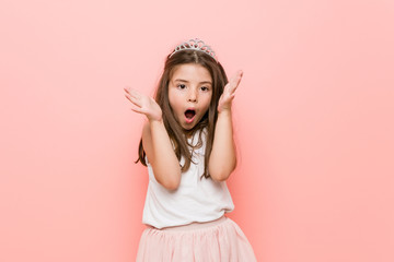 Little girl wearing a princess look celebrating a victory or success, he is surprised and shocked.